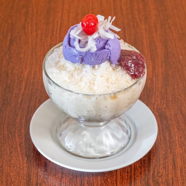 Halo-halo dessert with purple ube ice cream, red cherry, shredded coconut, and red jam.