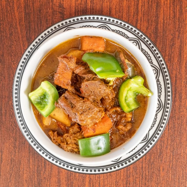 Hearty beef stew with carrots, potatoes, and green bell peppers in a decorative bowl.