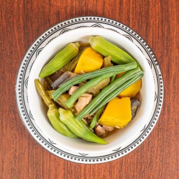 Overhead view of a bowl of pinakbet with okra, squash, green beans, and pork.