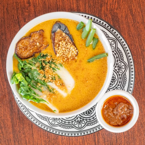 Overhead view of Kare-Kare, a Filipino peanut stew, with vegetables and meat, served with bagoong.